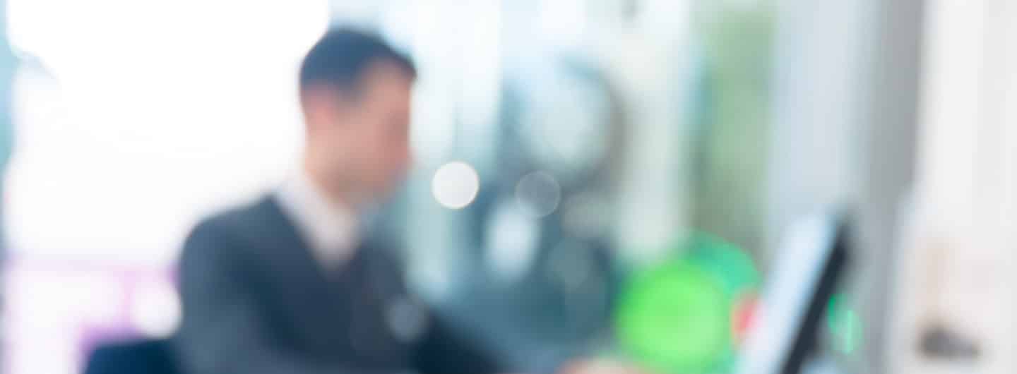 Blurred out man sitting at desk in front of computer